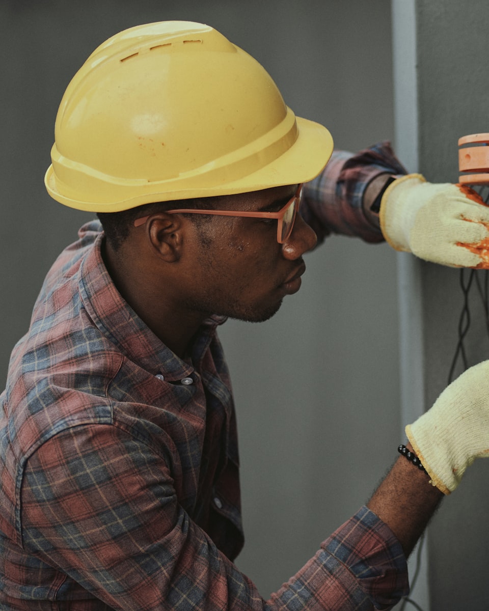 An operator in a hard hat working on an electrical panel — the trades Upgraid was built in