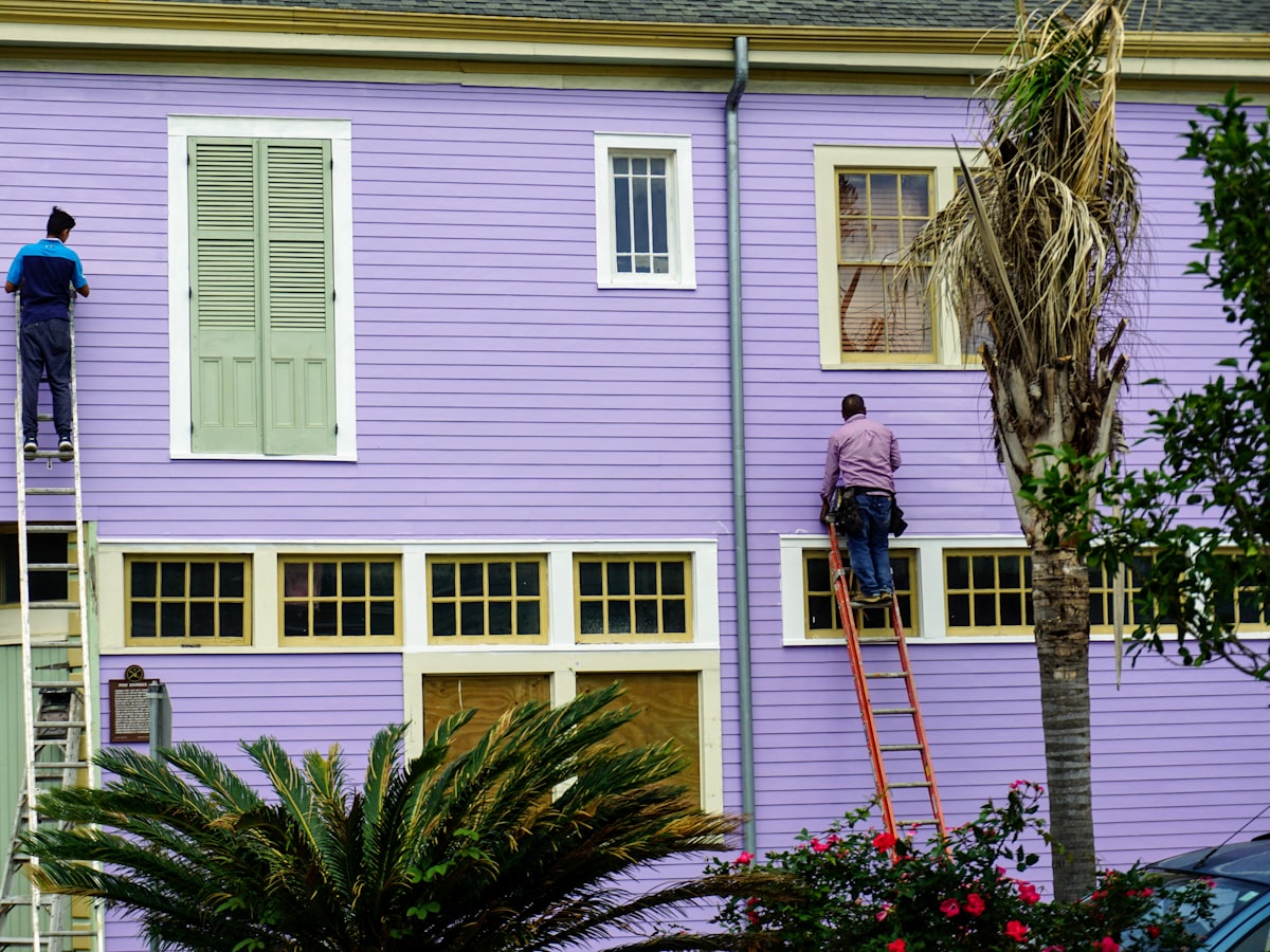 A two-man crew on ladders working the exterior of a house — the kind of business that runs on the phone